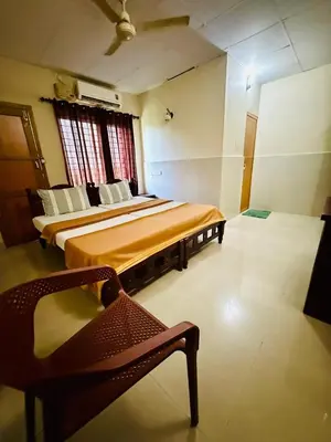 a bedroom with two beds and a chair in it at K M S Residency in Tirūr