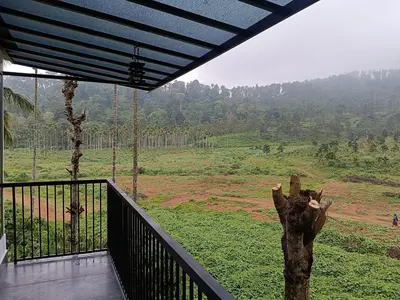 a room with a balcony with a view of a field at The Tree House in Vythiri