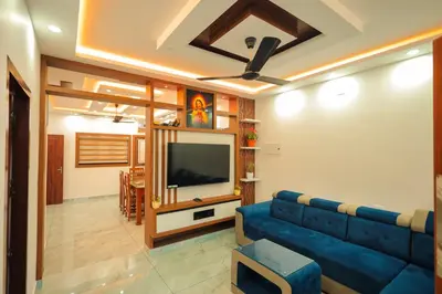 a living room with a blue couch and a flat screen tv at Wayanadanhuts Home Stay in Sultan Bathery