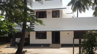a white house with a tree in front of it at Anand Bagh in Pollāchi