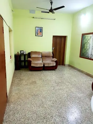 a living room with a couch and a ceiling fan at Anand Bagh in Pollāchi