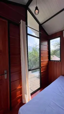 a bedroom with a bed and a large window at Alpine Zenith - Luxury Wooden Cottages in Meppādi