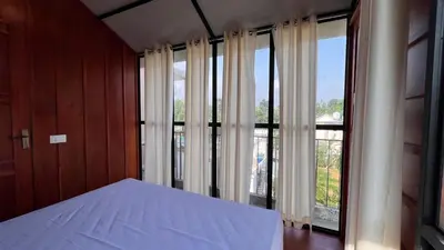 a bedroom with a bed and a large window at Alpine Zenith - Luxury Wooden Cottages in Meppādi