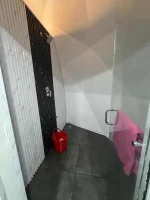 a small bathroom with a black door and a red bucket at Rivergreen resort in Athirappally