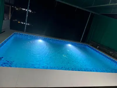 a large swimming pool with blue water at night at Rivergreen resort in Athirappally
