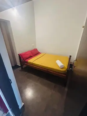 a bed in a room with a yellow and red mattress at ROYAL HOLIDAY HOMe in Ambalavayal
