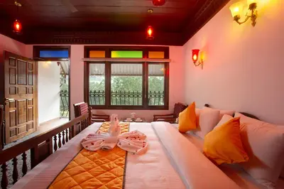 a bedroom with a bed with a table and a window at Koviloor Resort in Vattavada