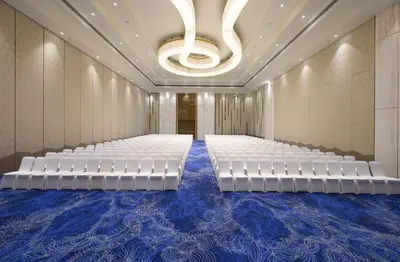 a conference room with white chairs and a chandelier at Merlis Hotel Coimbatore in Coimbatore