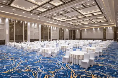 a large banquet hall with white tables and white chairs at Merlis Hotel Coimbatore in Coimbatore
