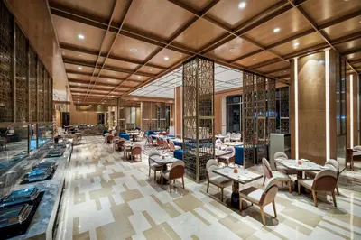 a restaurant with tables and chairs in a building at Merlis Hotel Coimbatore in Coimbatore