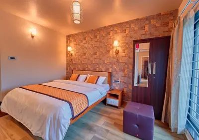 a bedroom with a bed and a brick wall at Ooty Blossom Retreat by VOYE HOMES in Ooty