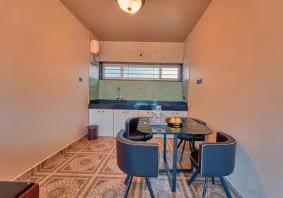 a kitchen with a table and chairs in a room at Ooty Blossom Retreat by VOYE HOMES in Ooty