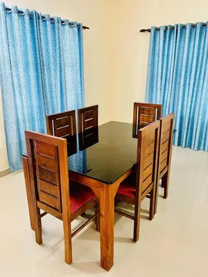a dining room table and chairs with blue curtains at 3BHK Spacious Villa near Rajagiri Hospital in Ernakulam