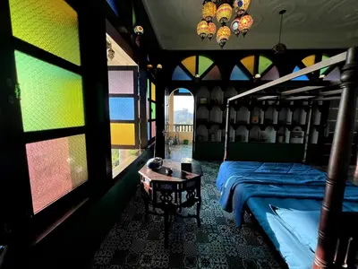a bedroom with a bed and a table and windows at Room Marakkech Mazha at Samava Farms Calicut in Kozhikode