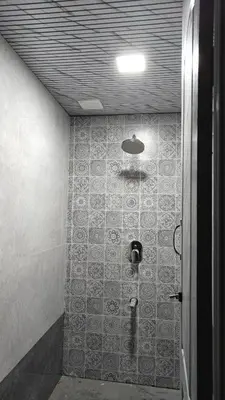 a bathroom with a shower with a tile wall at Eagles Nest in Dimbam