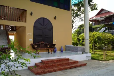 a house with a black door and a piano on the porch at Room Suvira at Samava Farms Calicut in Kozhikode
