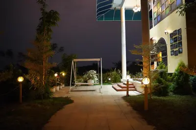 a courtyard at night with a swing and a building at Room Suvira at Samava Farms Calicut in Kozhikode