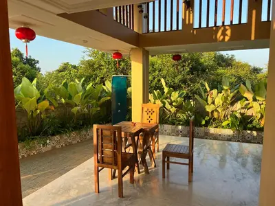 a porch with a table and chairs on a patio at Room Suvira at Samava Farms Calicut in Kozhikode