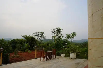 a table and chairs sitting on a patio with a view at Room Suvira at Samava Farms Calicut in Kozhikode