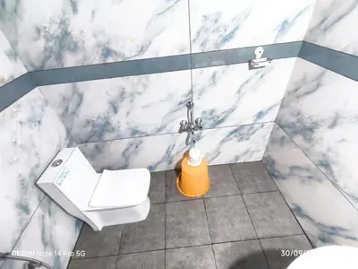 a bathroom with a white toilet and a sink at Diyara's Inn in Madikeri