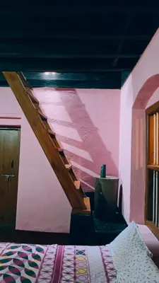 a bedroom with a pink wall with a wooden staircase at Coffeeisland vintage stay in Meenangadi