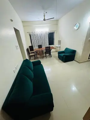 a living room with a green couch and a table at Harmony Nests in Thattakād