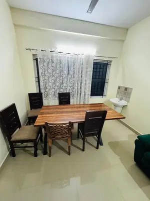 a dining room with a wooden table and chairs at Harmony Nests in Thattakād