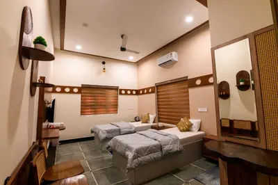 a bedroom with two beds and a mirror at Dr Indulekhas Ayurvedic Wellness & Rejuvenation in Tellicherry