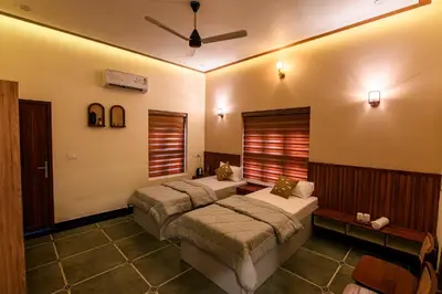 a bedroom with two beds and a ceiling fan at Dr Indulekhas Ayurvedic Wellness & Rejuvenation in Tellicherry