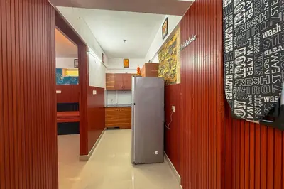 a kitchen with a refrigerator in the middle of a room at Mayflower Family Lounge -Cochin Airport in Nedumbassery