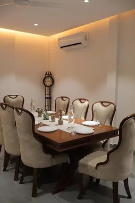 a dining room table with chairs and a clock at Kaayal Experience - Entire Home in Kozhikode in Kozhikode