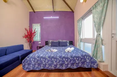 a purple bedroom with a bed and a blue couch at Spring Fields in Coimbatore