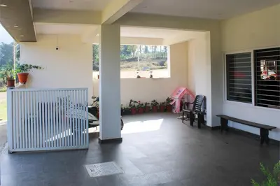 a porch of a house with a bench and a window at Jayasviinn Coorg in Virajpet