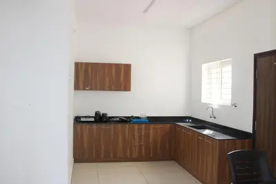 a kitchen with wooden cabinets and a sink at Jayasviinn Coorg in Virajpet