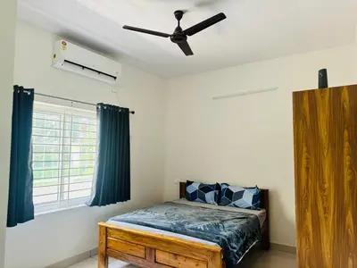 a bedroom with a bed and a ceiling fan at Jayasviinn Coorg in Virajpet