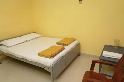 a small bedroom with a bed with yellow walls at AJ GrandInn in Podanūr