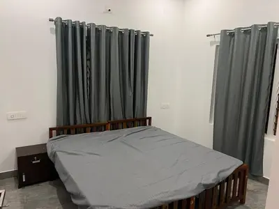 a bed with gray curtains in a bedroom at Mynakam - A peaceful escape in Vythiri