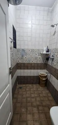 a bathroom with a toilet and a tiled floor at LBS Farmstay in Alāndurai