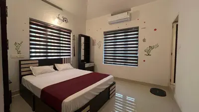 a bedroom with a bed and two windows at Cardamom cottage in Periya