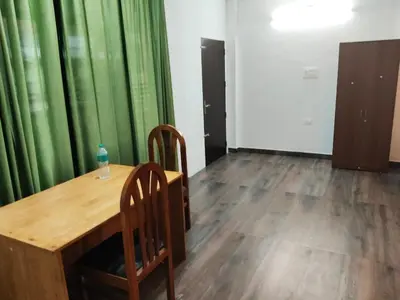 a table and chairs in a room with green curtains at DB GUEST HOUSE ARIMPUR - Unmarried couples and Stag groups not allowed in Trichūr