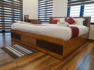 a large bed in a room with wooden floors at VGK Residency in Wayanad