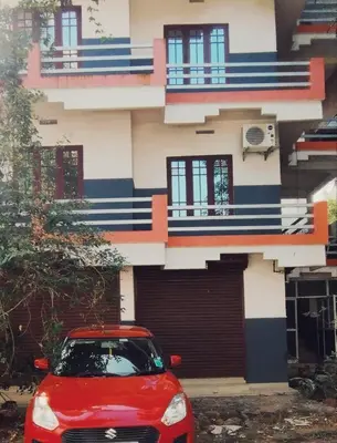 a red car parked in front of a building at Raya Casa Couple Suite 101 in Guruvāyūr