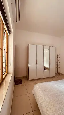 a bedroom with white cabinets and a window at Snehanilayam in Trichūr