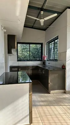a large kitchen with black cabinets and windows at Snehanilayam in Trichūr