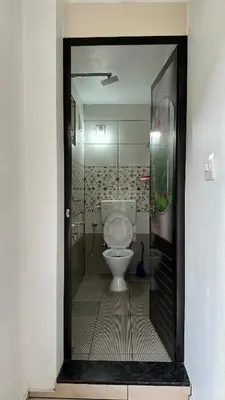 a bathroom with a white toilet in a room at Snehanilayam in Trichūr