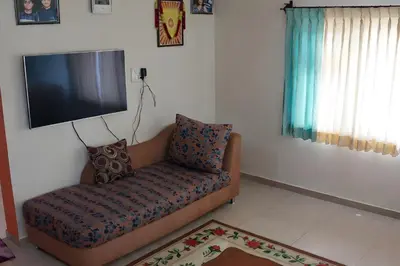 a living room with a couch and a flat screen tv at Aarroh villa in Coonoor