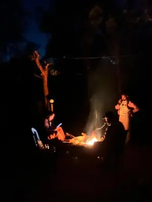 a group of people standing around a fire at night at Oryx Villai in Vythiri