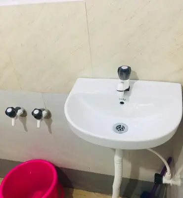 a white sink in a bathroom with a pink bucket at Vintage Breeze Home Stay in Madikeri
