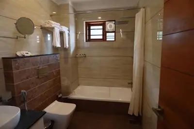 a bathroom with a tub and a toilet and a sink at Devalokam Edappal in Edappāl