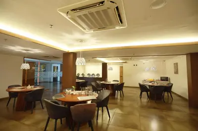 a restaurant with tables and chairs and a fan at Devalokam Edappal in Edappāl